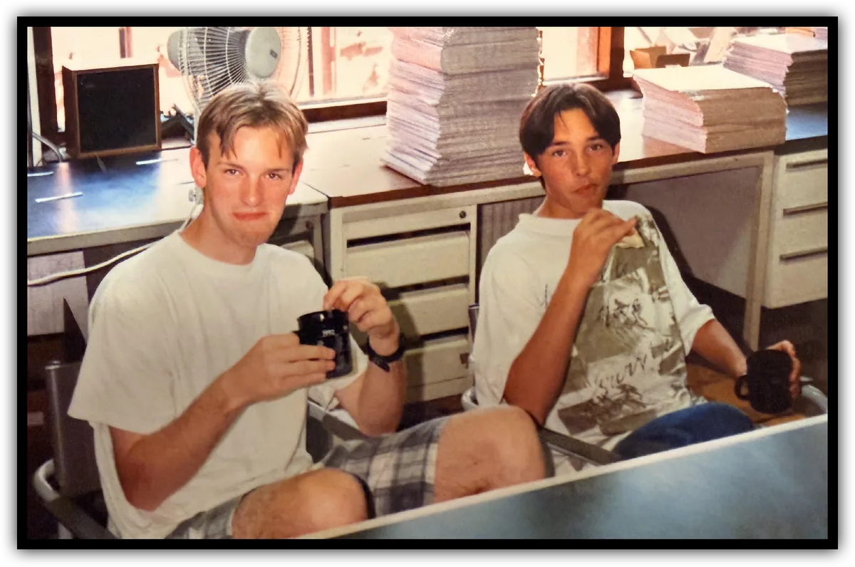 Bowie and Jeroen Derwort as teenagers, each holding a coffee mug, at a desk stacked with paper
